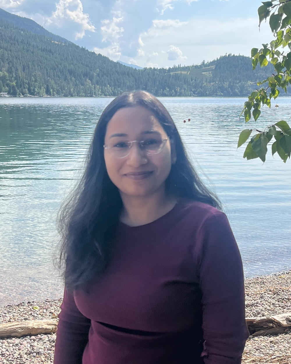 Deepika poses in a purple shirt in front of Yellow Bay at Flathead Lake.
