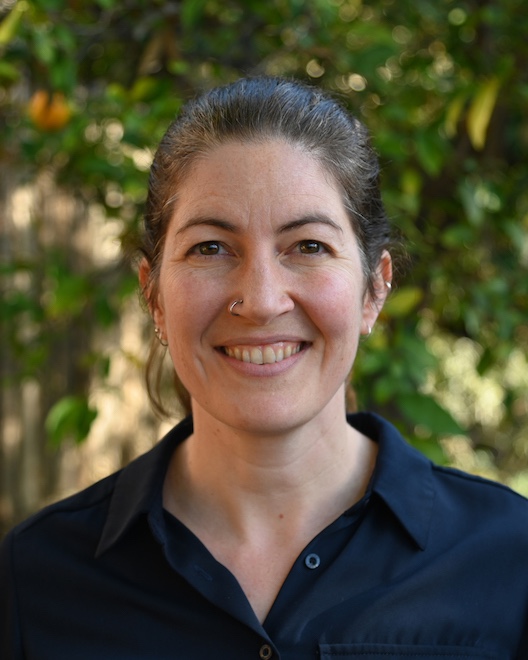 Emily smiles at the camera wearing a navy shirt.
