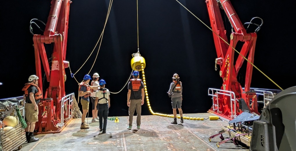 The SUBSEA team readies a Wirewalker for deployment from a research ship at night.