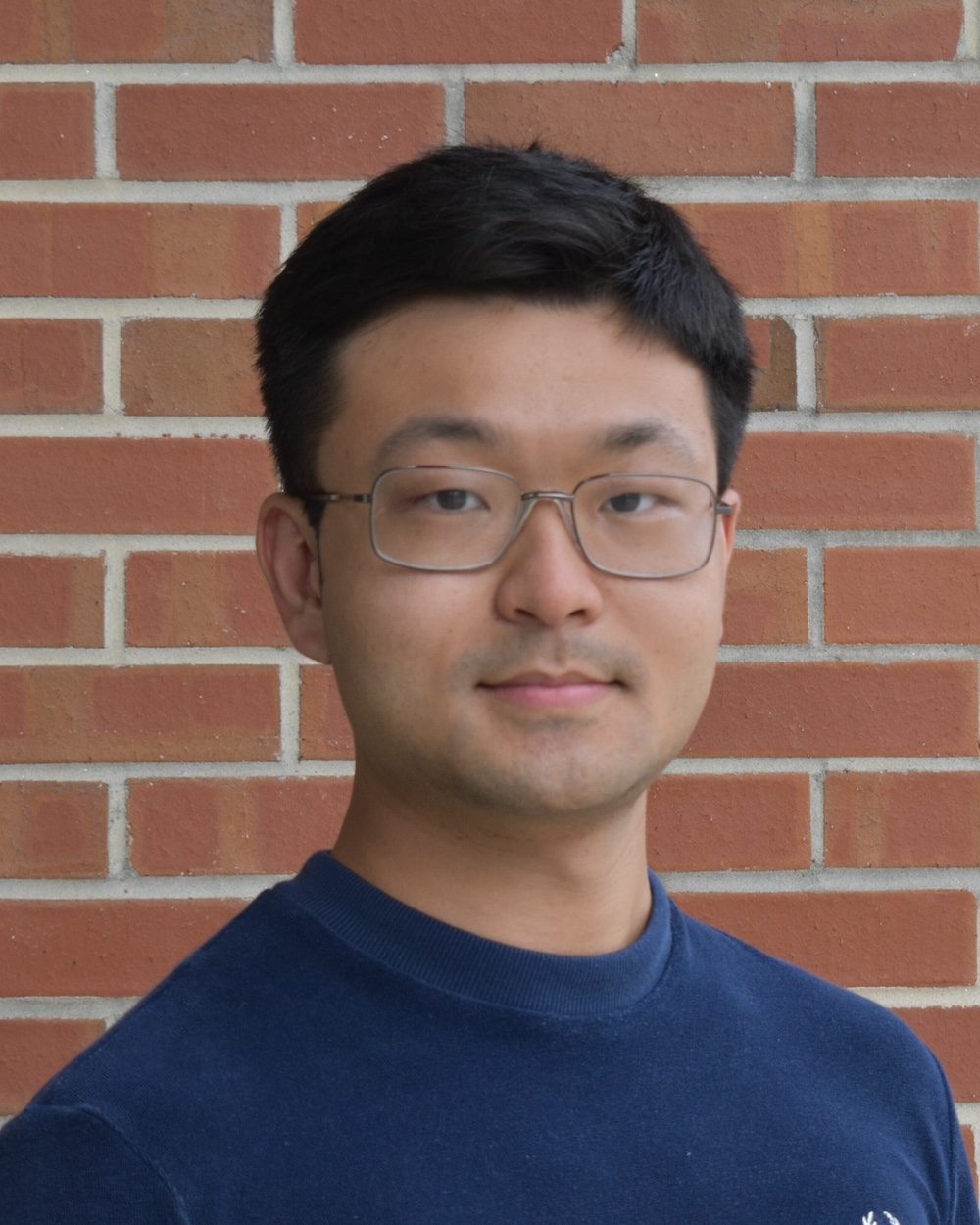 Zhou poses in front of a brick background.